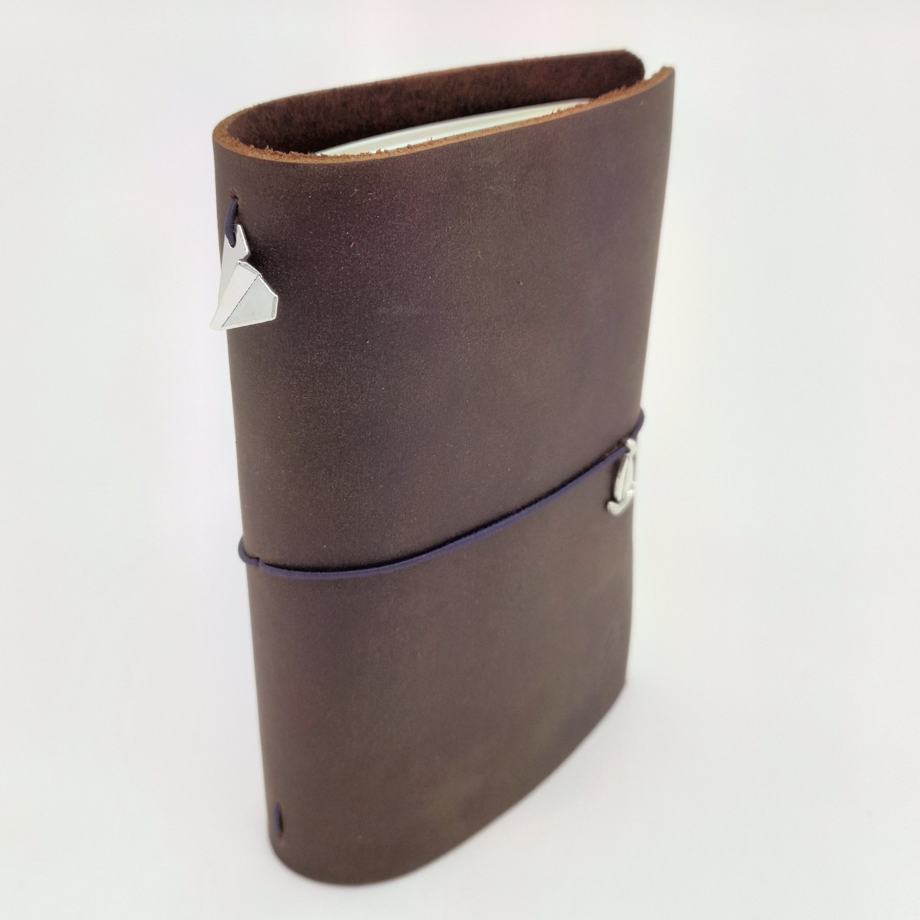 Pocket size dark brown leather traveler's notebook with a sailboat charm